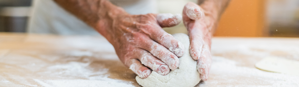 KI generiert: Hände kneten Teig auf einer bemehlten Oberfläche.