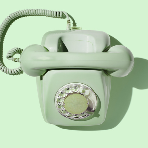KI generiert: Ein mintgrünes Wählscheibentelefon vor einem passenden Hintergrund.