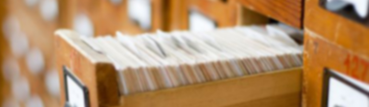 KI generiert: Ein hölzerner Karteischrank mit halbherausgezogener Schublade voller Karten.