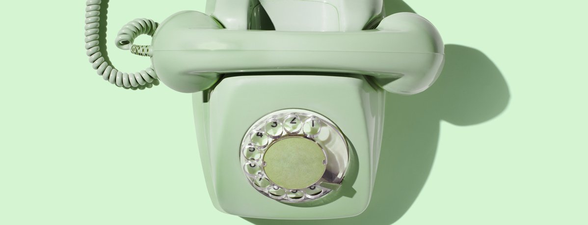 KI generiert: Ein mintgrünes Wählscheibentelefon auf hellgrünem Hintergrund.