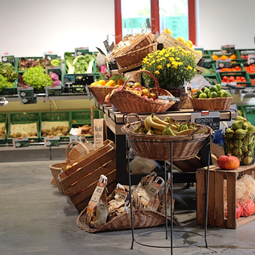 KI generiert: Frisches Obst und Gemüse in Körben und Kisten in einem Laden. Text: "Nektarinen", "Nicht alles", "WIR".