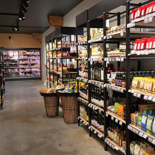 KI generiert: Supermarktgang mit Regalen voller Lebensmittel; Blick auf Kühlregal im Hintergrund.