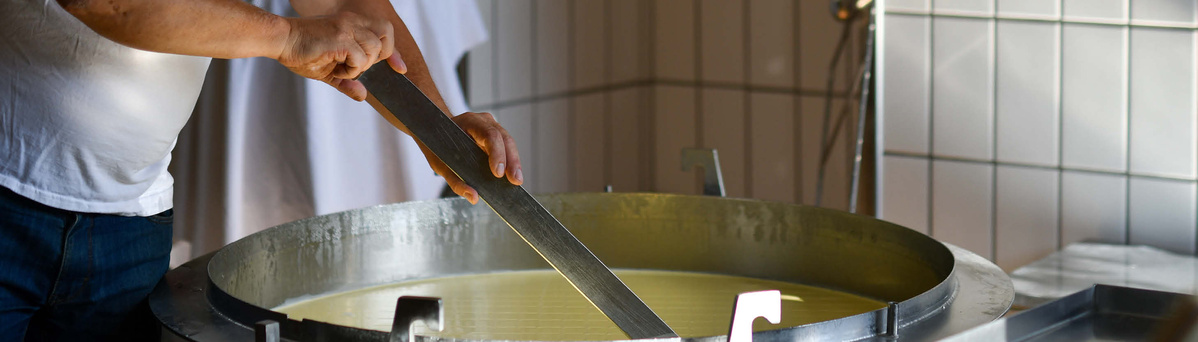 KI generiert: Eine Person rührt in einem großen Metallkessel.