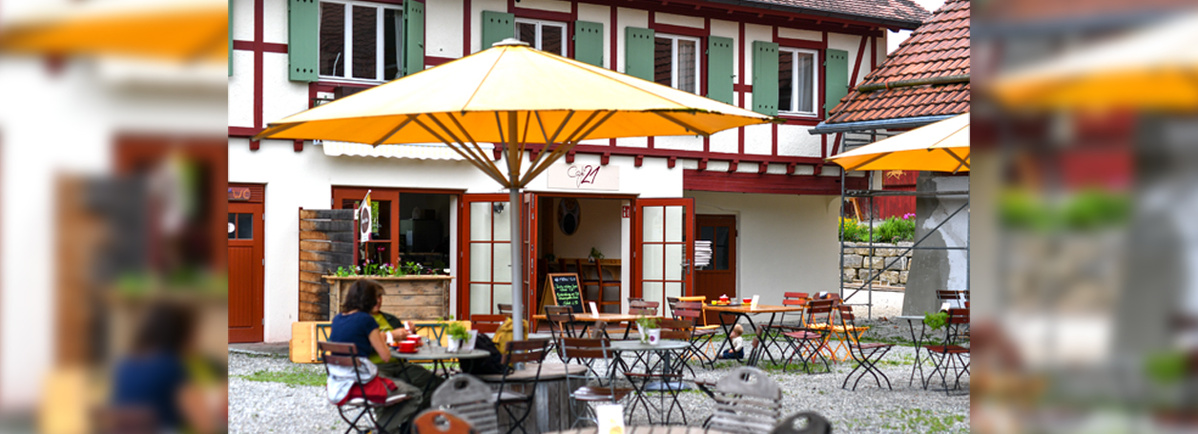 KI generiert: Ein Café im Freien mit gelben Sonnenschirmen und Sitzplätzen.