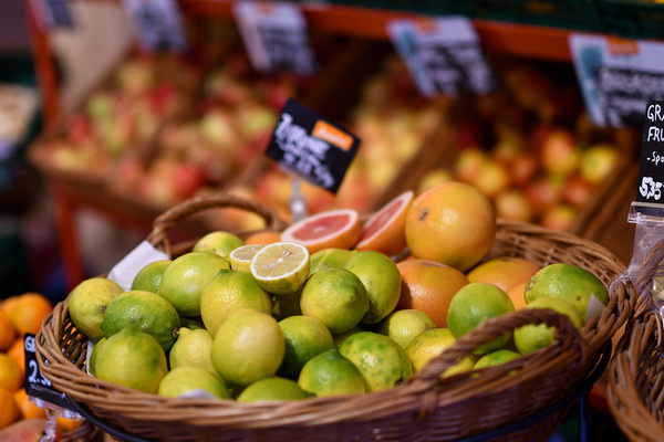 KI generiert: Ein Korb mit Limetten und Grapefruit auf einem Marktstand. Links Preisschilder.