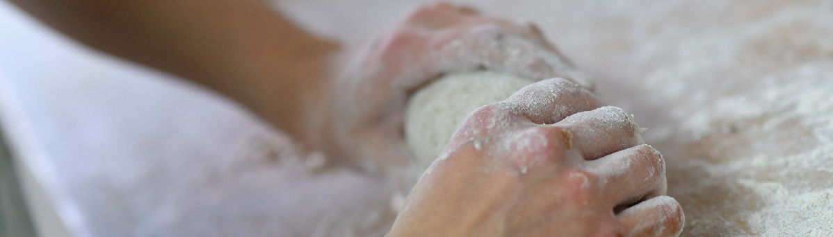 KI generiert: Hände kneten Teig auf bemehlter Oberfläche.