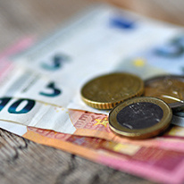 KI generiert: Euro-Scheine und Münzen liegen unscharf auf einem Holztisch. Kein Text vorhanden.