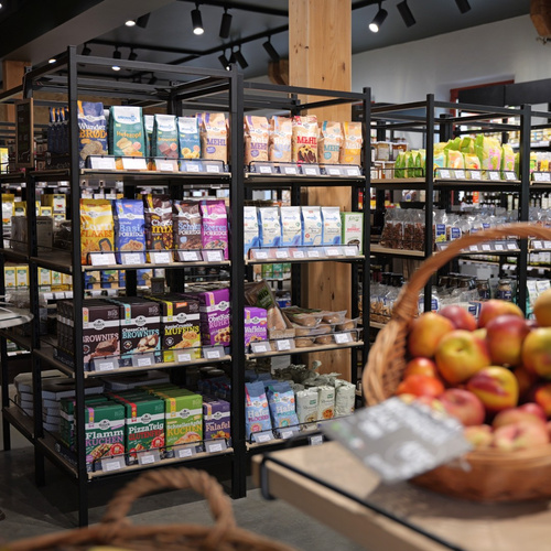 KI generiert: Regale in einem Laden mit Bio-Lebensmitteln und ein Korb voller Äpfel im Vordergrund.